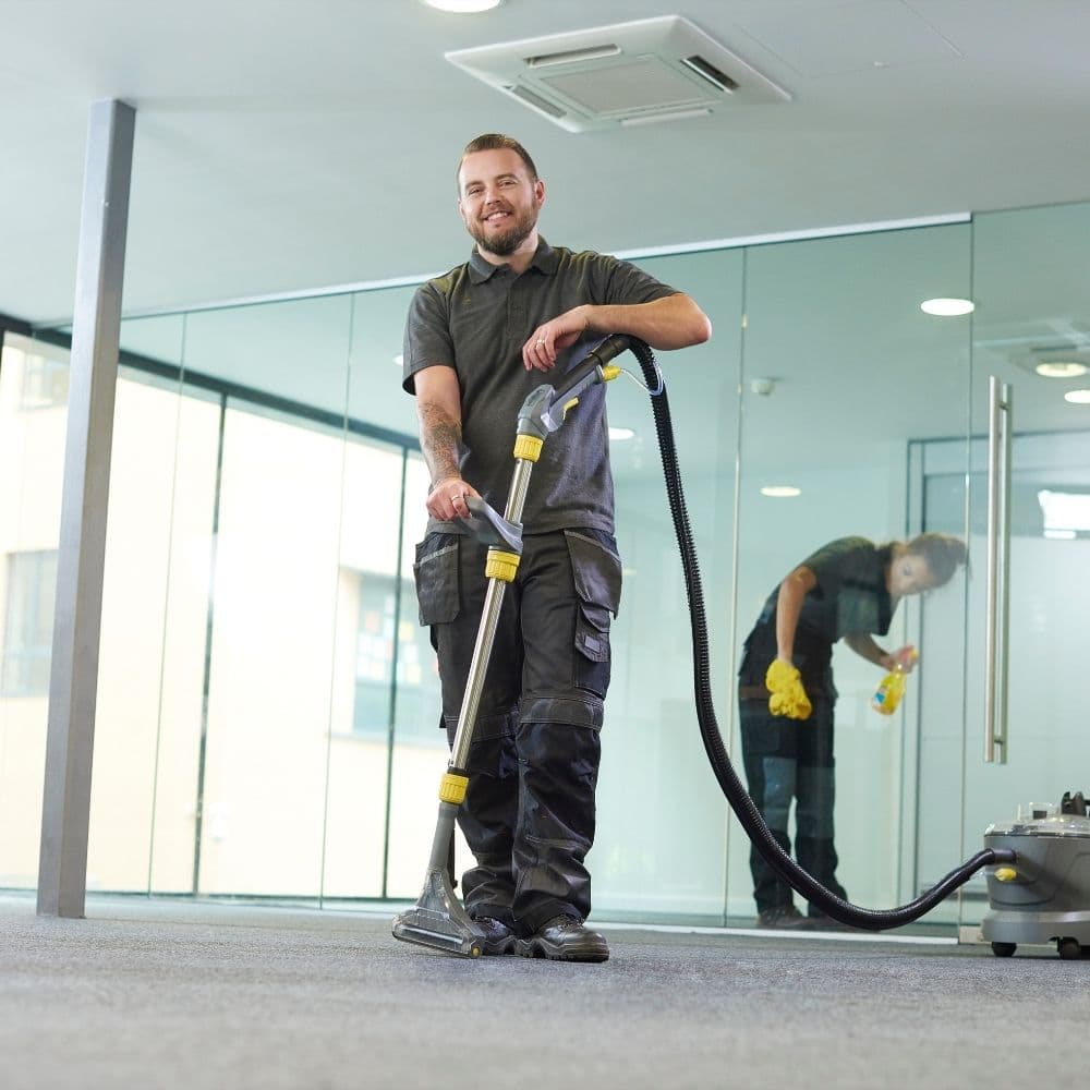 a man cleaning the office carpet through a vacuum cleaner